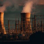A nuclear power plant's cooling towers emit steam at sunset, highlighting industrial infrastructure.