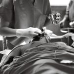 Black and white image of a medical professional performing a procedure in an operating room.