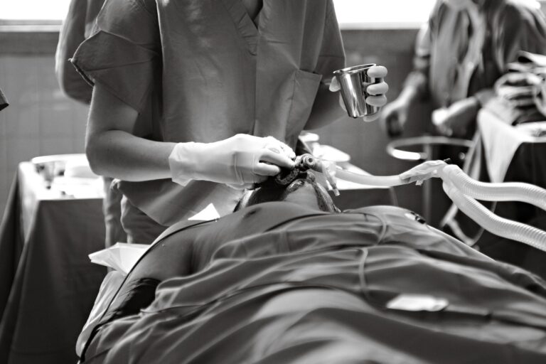 Black and white image of a medical professional performing a procedure in an operating room.