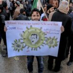 High angle of ethnic male activist with poster standing on crowded street at demonstration against policy