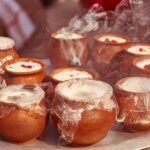 Close-up of steaming Indian desserts in clay pots, infused with aromatic spices and garnished with nuts.