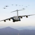 A formation of military cargo aircraft flying over a mountainous landscape, showcasing aviation power.