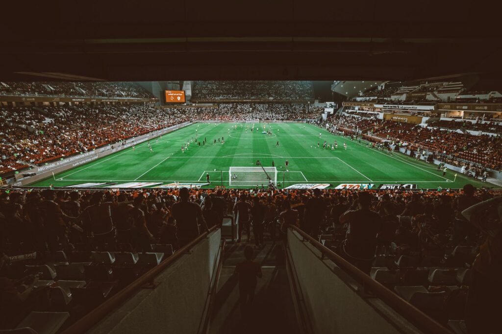 Aerial shot of a thrilling football match in a packed stadium, with enthusiastic fans.