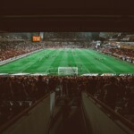 Aerial shot of a thrilling football match in a packed stadium, with enthusiastic fans.