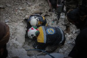 Rescue workers from civil defense searching rubble for survivors in Idlib, Syria, post-disaster.