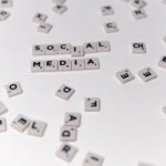 White Scrabble tiles forming the phrase 'social media' on a scattered background.