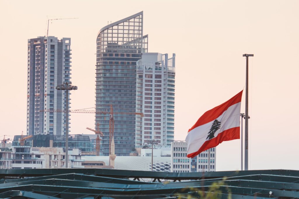 Urban skyline of Beirut with a prominent Lebanese flag gently waving at sunset.