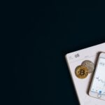 Smartphone displaying cryptocurrency data next to Bitcoin on a calendar offers finance and technology insights.