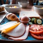 A delectable European breakfast spread featuring bread, cheese, and fresh vegetables on a tray.