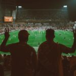 A vibrant football match with fans cheering in an illuminated stadium.