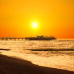 A stunning view of Brighton Pier silhouetted against a golden sunset over the sea waves.
