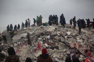 Survivors and rescuers search through rubble after a disaster in Idlib, Syria.