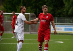 Players engage in an intense football match on a green outdoor pitch.