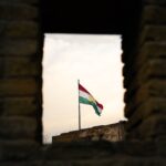 A view of the Kurdistan flag waving through the ancient brick wall of the Erbil Citadel in Iraq.