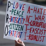 A protest sign emphasizing pro-love, peace, and integrity, against hate and war.
