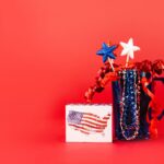 A festive display of red, white, and blue patriotic decor against a vibrant red background, perfect for July 4th celebrations.