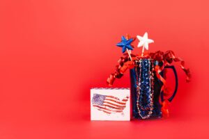 A festive display of red, white, and blue patriotic decor against a vibrant red background, perfect for July 4th celebrations.
