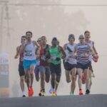 Dynamic shot of marathon runners competing in a misty urban setting, emphasizing endurance and athleticism.