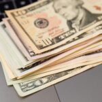 Stack of US dollar bills on a keyboard, symbolizing digital finance and wealth.