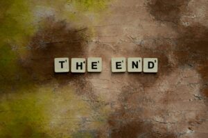 Scrabble tiles forming 'The End' on a textured rustic background, conveying closure.