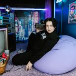 A young person relaxing with vintage tech in a retro-themed room full of nostalgic details.