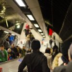 Commuters using crowded escalators in an indoor metro station setting.