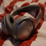 Close-up of silver wireless headphones resting on red and white patterned fabric.