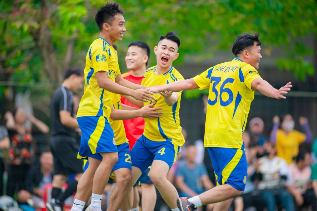 Group of young men celebrating a football victory outdoors in Hanoi.
