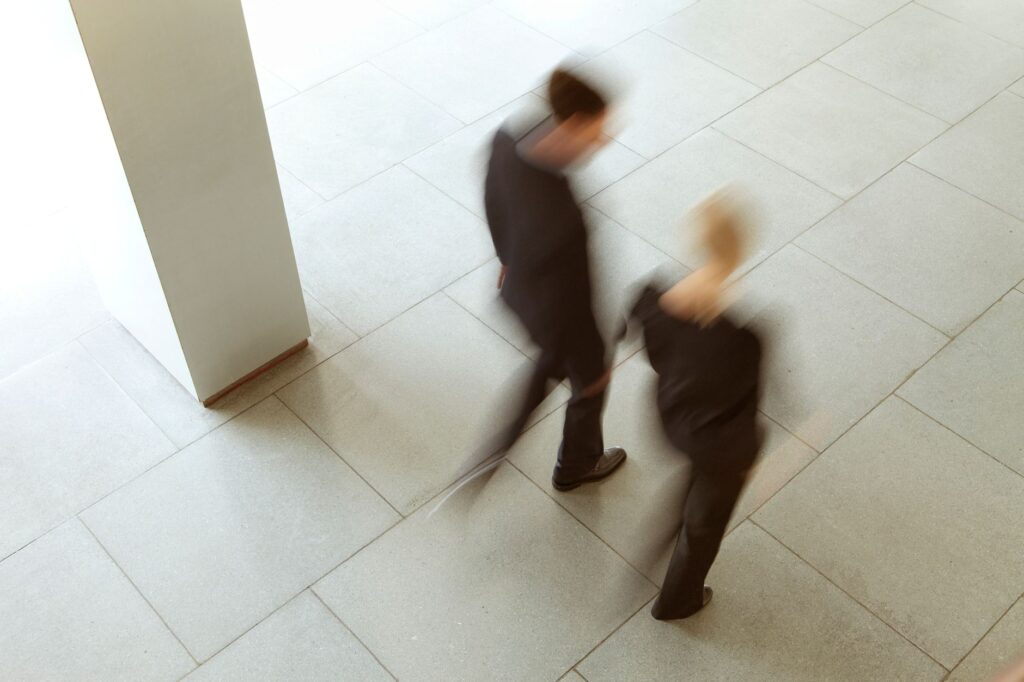 Artistic blurred photograph of two people walking in an urban environment, capturing dynamic motion.