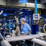 Female textile worker operating machinery in an Indian factory, showcasing industrial production.
