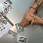 A handcuffed individual examines evidence photos and documents during an investigation.