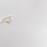 Minimalist image of a robotic hand reaching out on a white background.