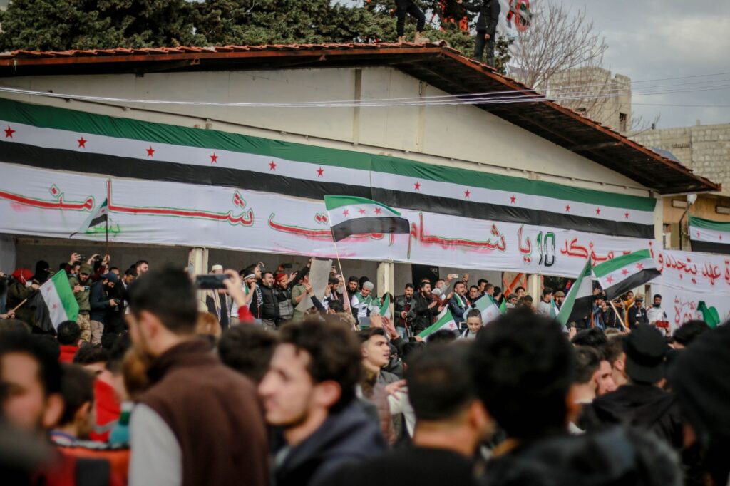 Protesters gather with Syrian flags in an Idlib street demonstration.
