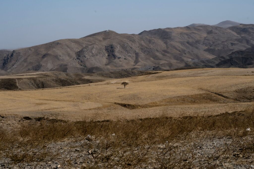 Expansive desert landscape with rolling hills and sparse vegetation in Mashhad, Iran.