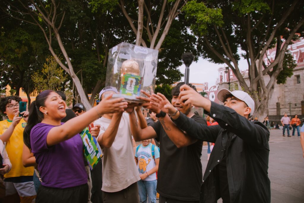 Cheerful group of people celebrating outdoors while holding a trophy together.