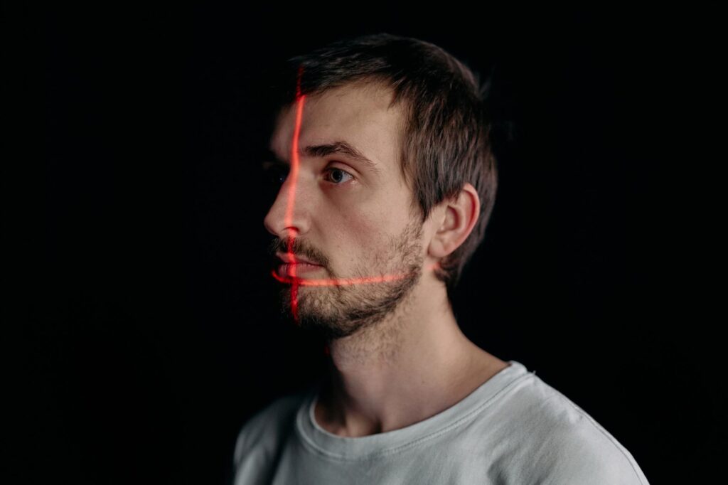 A man undergoes a facial recognition scan with a laser grid in a studio setting.