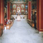Peaceful interior of a Buddhist temple featuring an altar and a monk seated nearby.