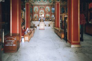 Peaceful interior of a Buddhist temple featuring an altar and a monk seated nearby.
