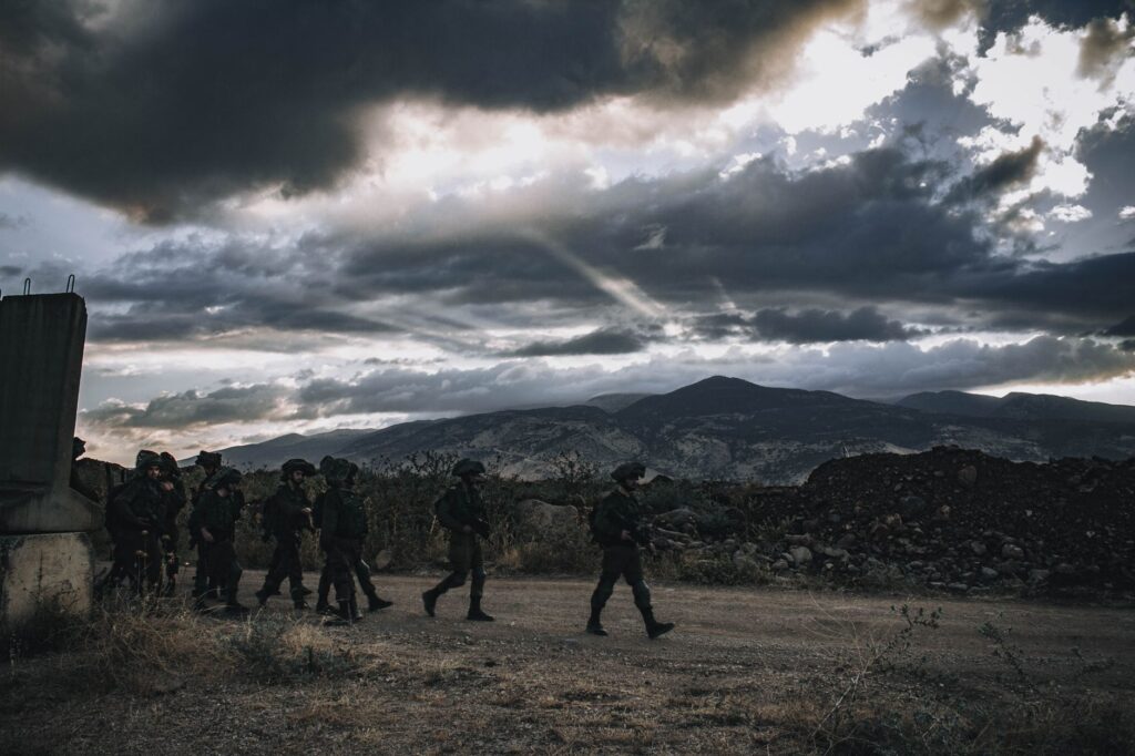 A group of soldiers march through a rugged landscape under a threatening sky in Israel.