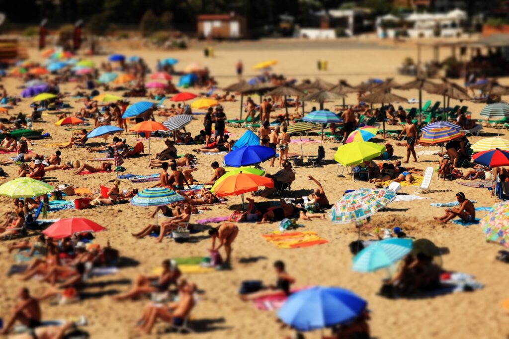 Vibrant beach scene with sunbathers and colorful umbrellas on a sunny day.