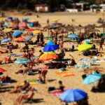 Vibrant beach scene with sunbathers and colorful umbrellas on a sunny day.