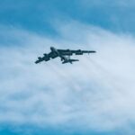 A B-52 Stratofortress aircraft soars through a clear blue sky on a sunny day.