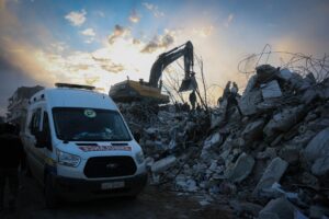 Emergency responders clear rubble in Idlib, Syria after a natural disaster. Scene highlights urgency and recovery efforts.