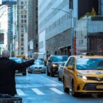 A man hailing a yellow taxi in bustling NYC street, capturing urban life.